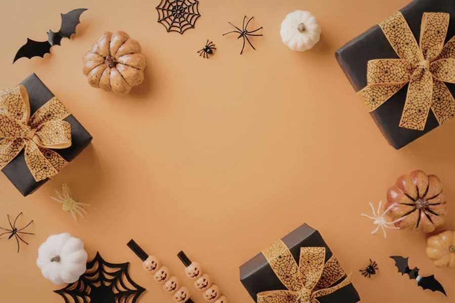 Assortiment de cadeaux Halloween noirs avec rubans toile d'araignée, citrouilles et araignées sur fond orange