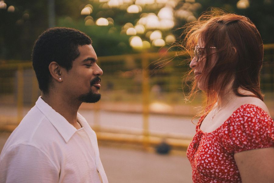Une séance engagement avant le mariage d'un couple se regardant tendrement au coucher du soleil, avec des lumières dorées en arrière-plan.