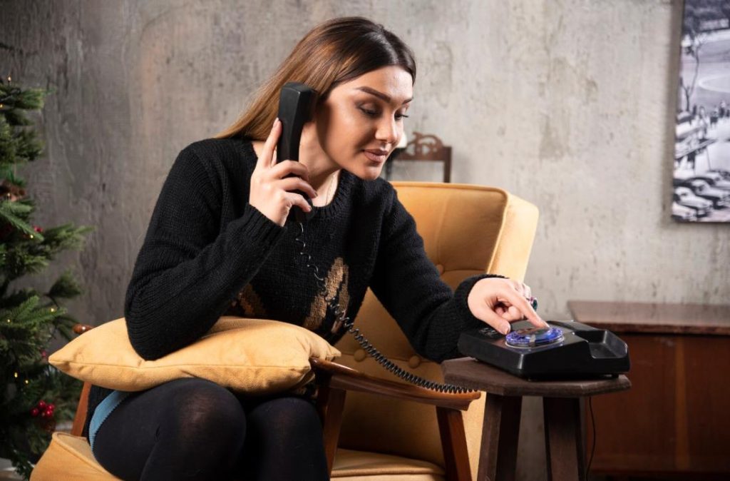 Jeune femme assise dans un fauteuil laissant un message vocal pour tester le fonctionnement livre d or audio telephone mariage.