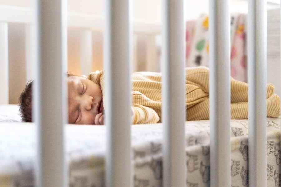 Bébé endormi dans un lit à barreaux avec une literie pour le sommeil de bébé adaptée et sécurisée.